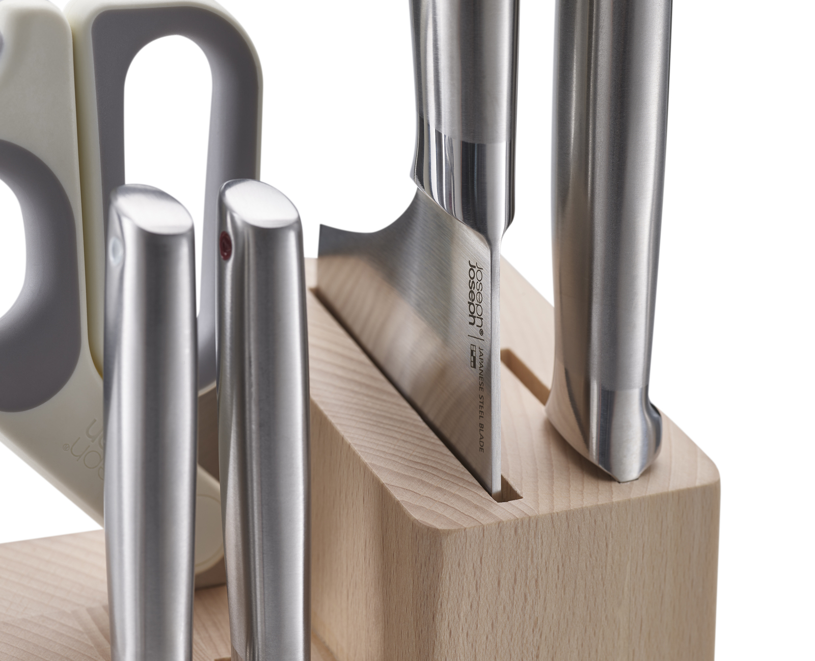 Primer plano de cuchillos en un bloque de madera. Los cuchillos son de acero inoxidable. A la izquierda hay un afilador.