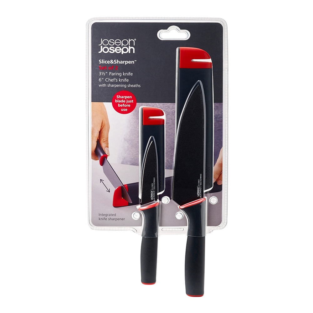 Un juego de cuchillos en embalaje. Incluye cuchillos para pelar y de chef con hojas negras, detalles rojos y afiladores integrados. Marca: Joseph Joseph.