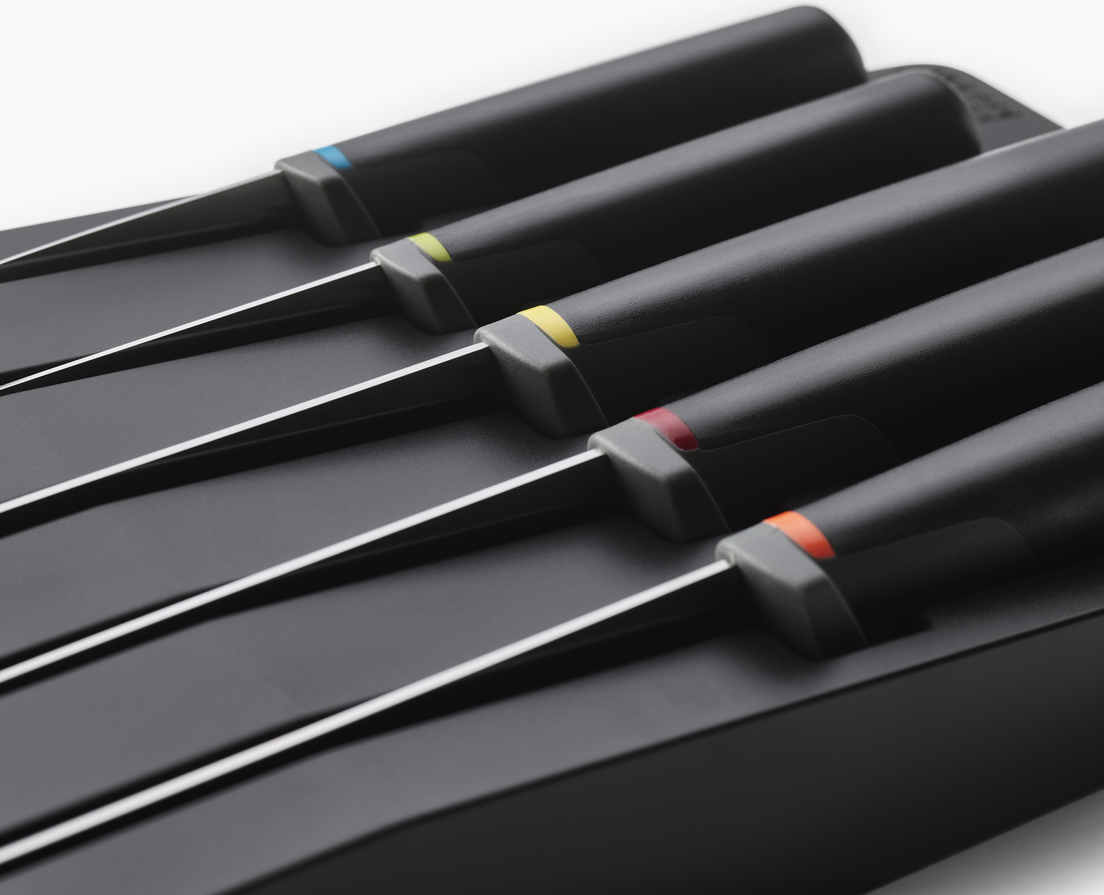 Juego de cuatro cuchillos negros en un soporte. Cada cuchillo tiene un anillo de color diferente: azul, verde, rojo, naranja. Fondo blanco.