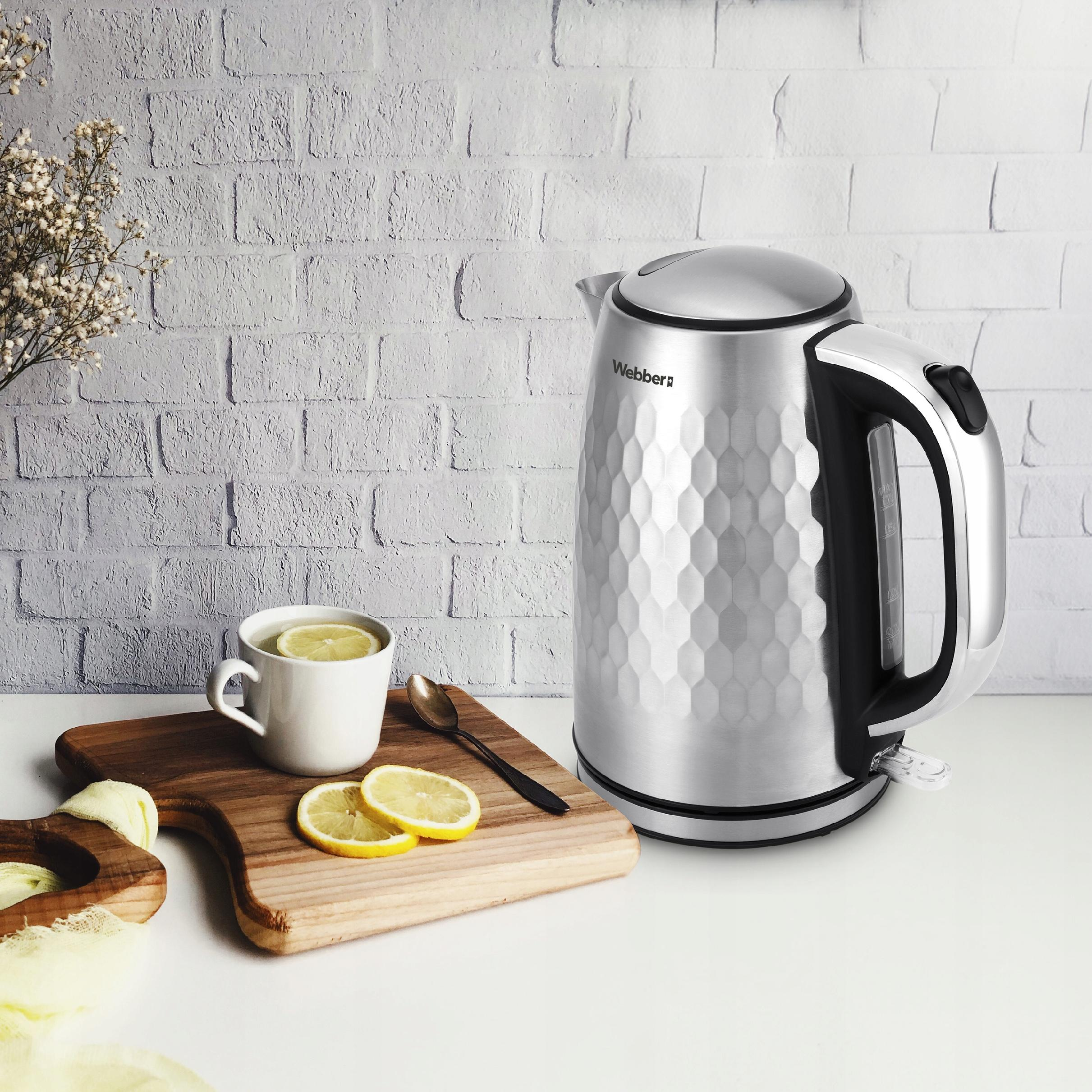 Metalowy czajnik, filiżanka herbaty z plasterkami cytryny, drewniana deska, łyżka i plasterki cytryny na stole.