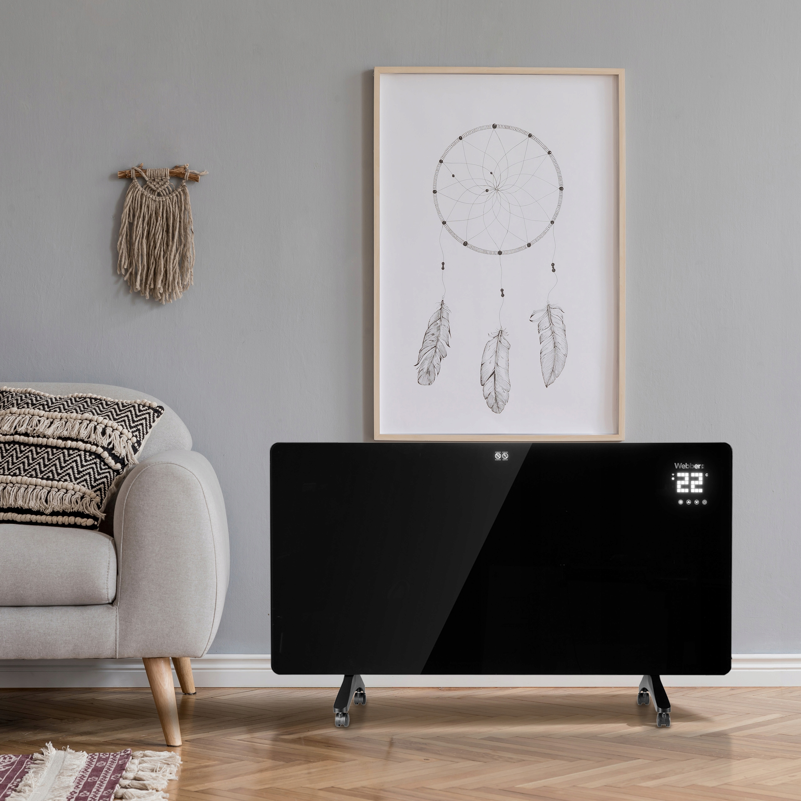 Nowoczesny salon z czarnym grzejnikiem, oprawionym łapaczem snów, sofą i drewnianą podłogą.