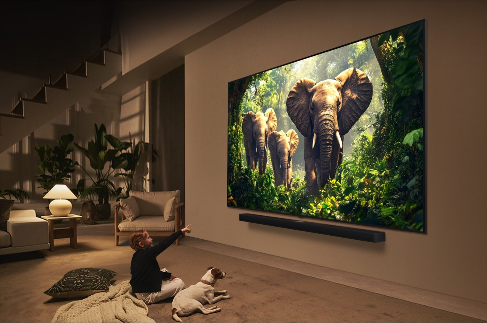 Un bambino e un cane guardano la TV con elefanti. Soundbar sotto. Soggiorno con piante e una lampada visibile.