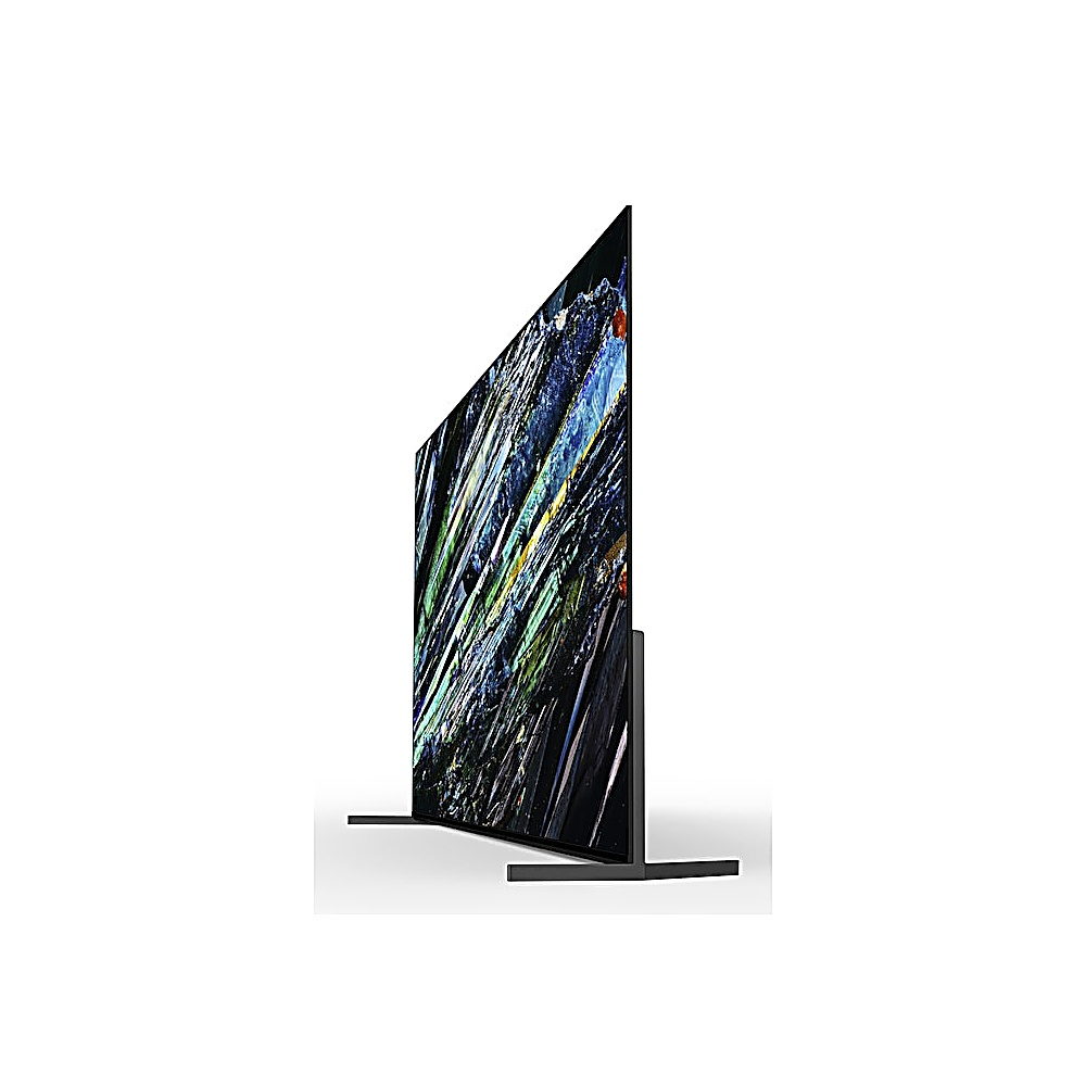 Un televisor grande y moderno, ligeramente inclinado, muestra arte abstracto colorido. El televisor está sobre un soporte, sobre un fondo blanco.