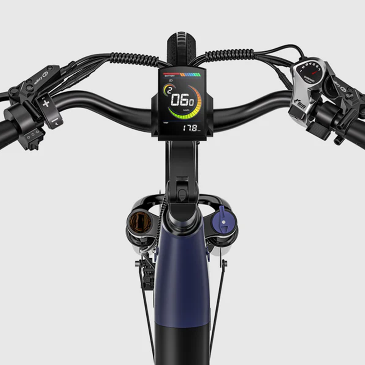 Zbliżenie kierownicy roweru elektrycznego. Wyświetlacz pokazuje prędkość 06.0. Kierownica czarna, widoczne różne kontrolki i kable.