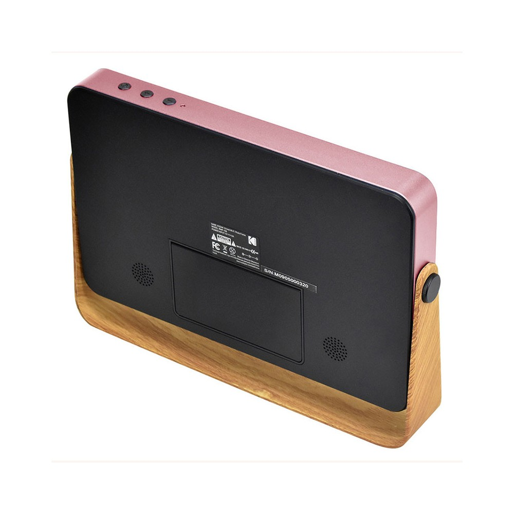 Una radio despertador rosa dorado y negro se encuentra sobre una base de madera. Tiene botones en la parte superior y un altavoz al frente.