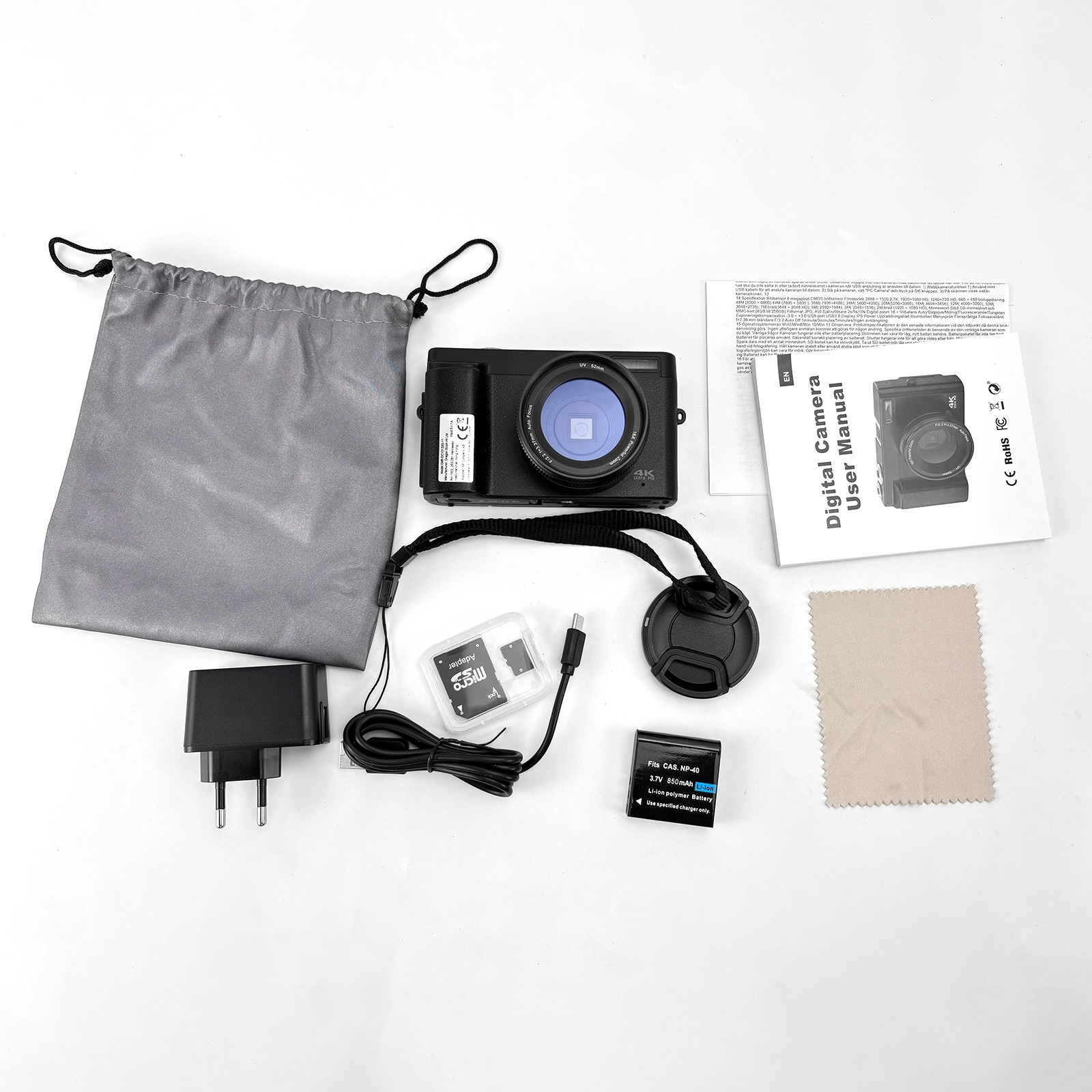 Czarny zestaw aparatu na białej powierzchni. Zawiera aparat, torbę, ładowarkę, baterię, instrukcje i akcesoria.