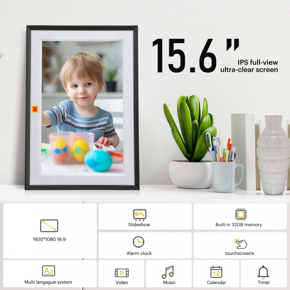 Un marco de fotos digital muestra una pintura infantil. Tiene una planta, bolígrafos y un jarrón en un estante blanco. Texto: Pantalla de 15,6 pulgadas.