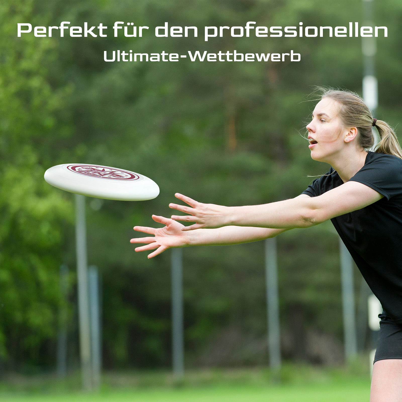 Eine Frau in Schwarz greift nach einer weißen Frisbeescheibe mit rotem Design. Grüner Hintergrund, Bäume.