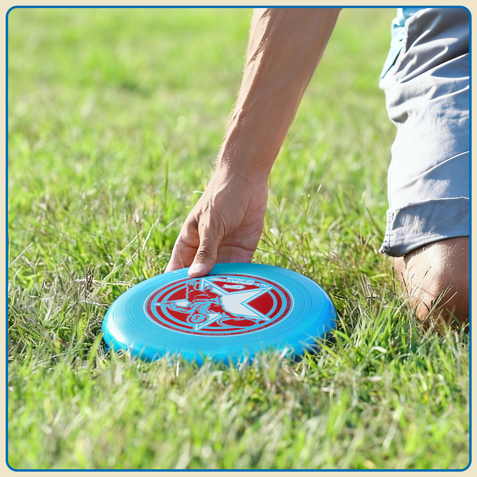 Eine Person legt eine blaue Frisbeescheibe auf grünes Gras. Die Frisbee hat ein rot-weißes Design.