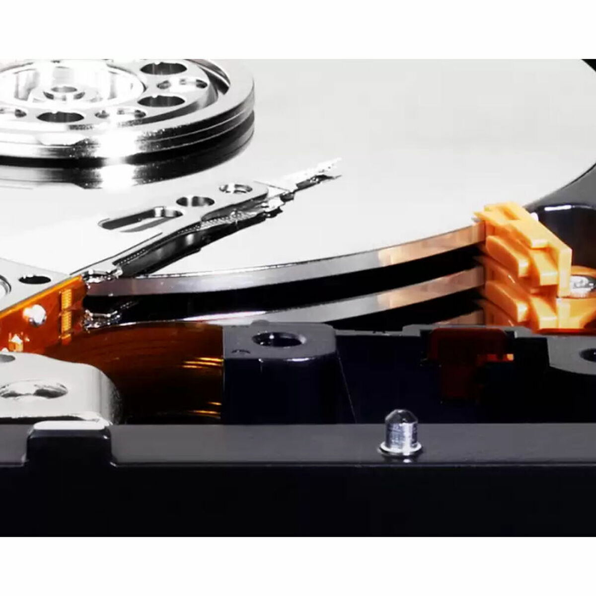 Zbliżenie mechanizmu dysku twardego. Widoczny srebrny dysk, ramię i pomarańczowe złącze. Obecna jest również czarna obudowa i śruby.