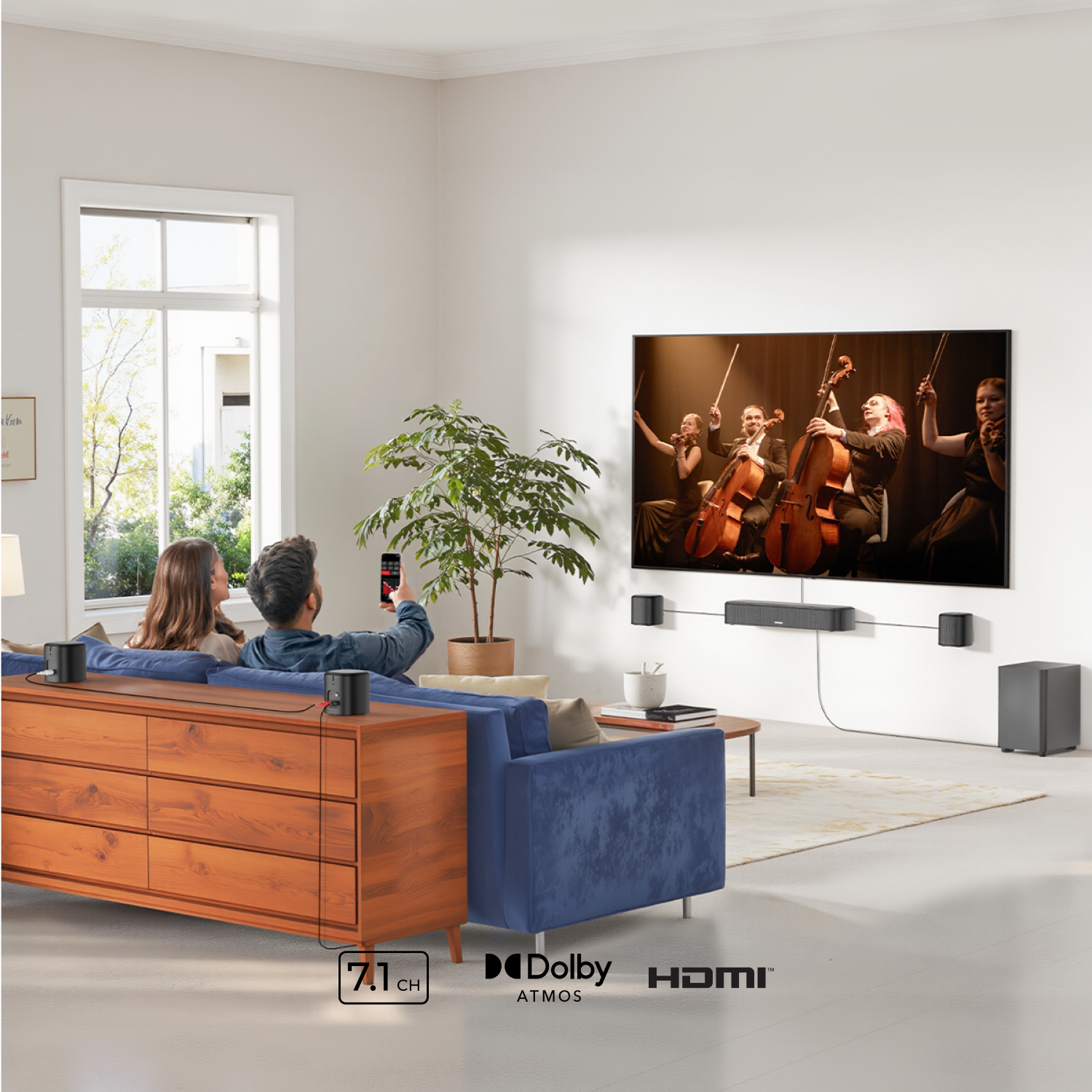 Paar schaut Fernseher mit Streichquartett. Soundsystem vorhanden. Holzkommode und blaues Sofa. Fenster und Pflanze im Hintergrund.