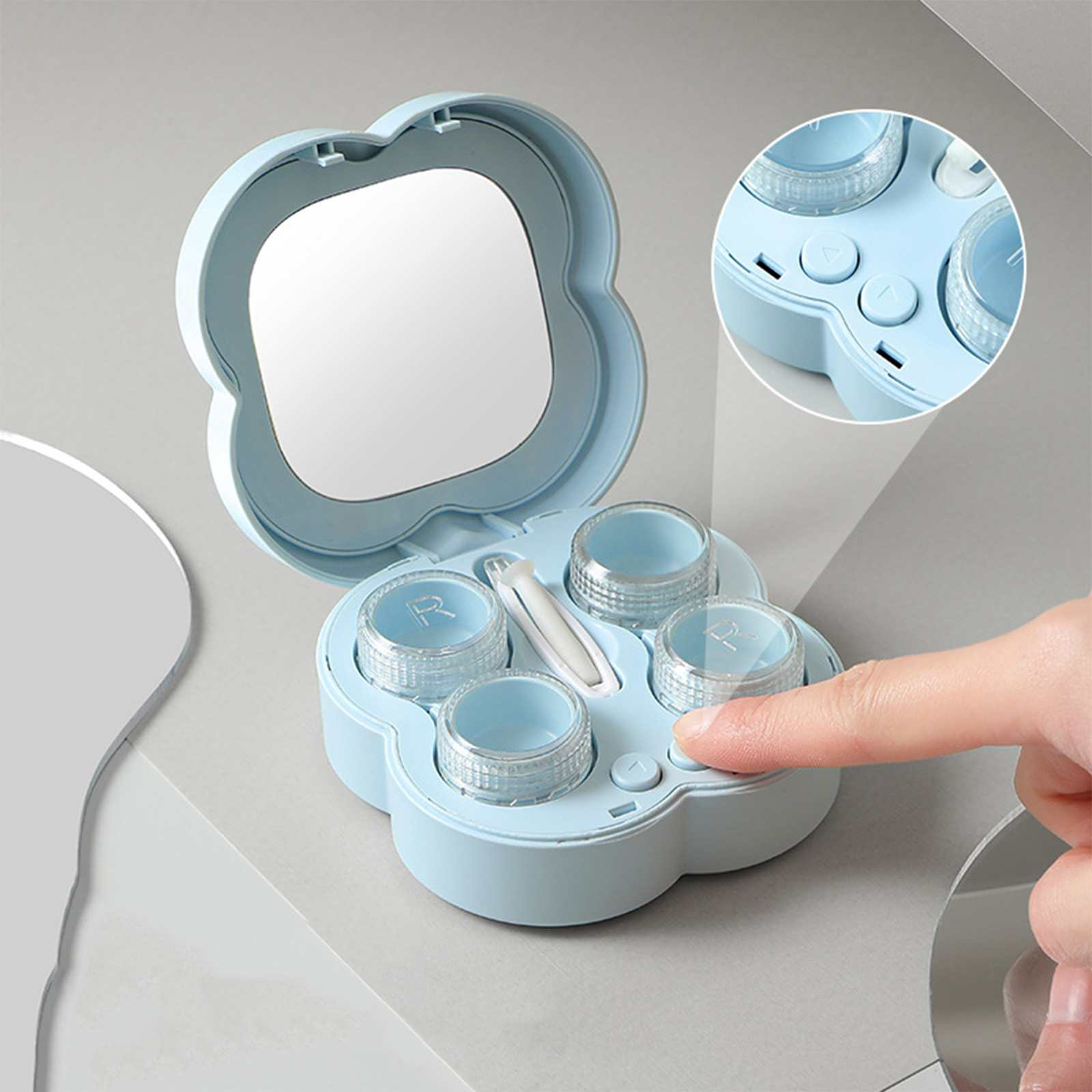 Hellblaue Kontaktlinsen-Etui mit Spiegel und vier Behältern. Ein Finger drückt einen Knopf.