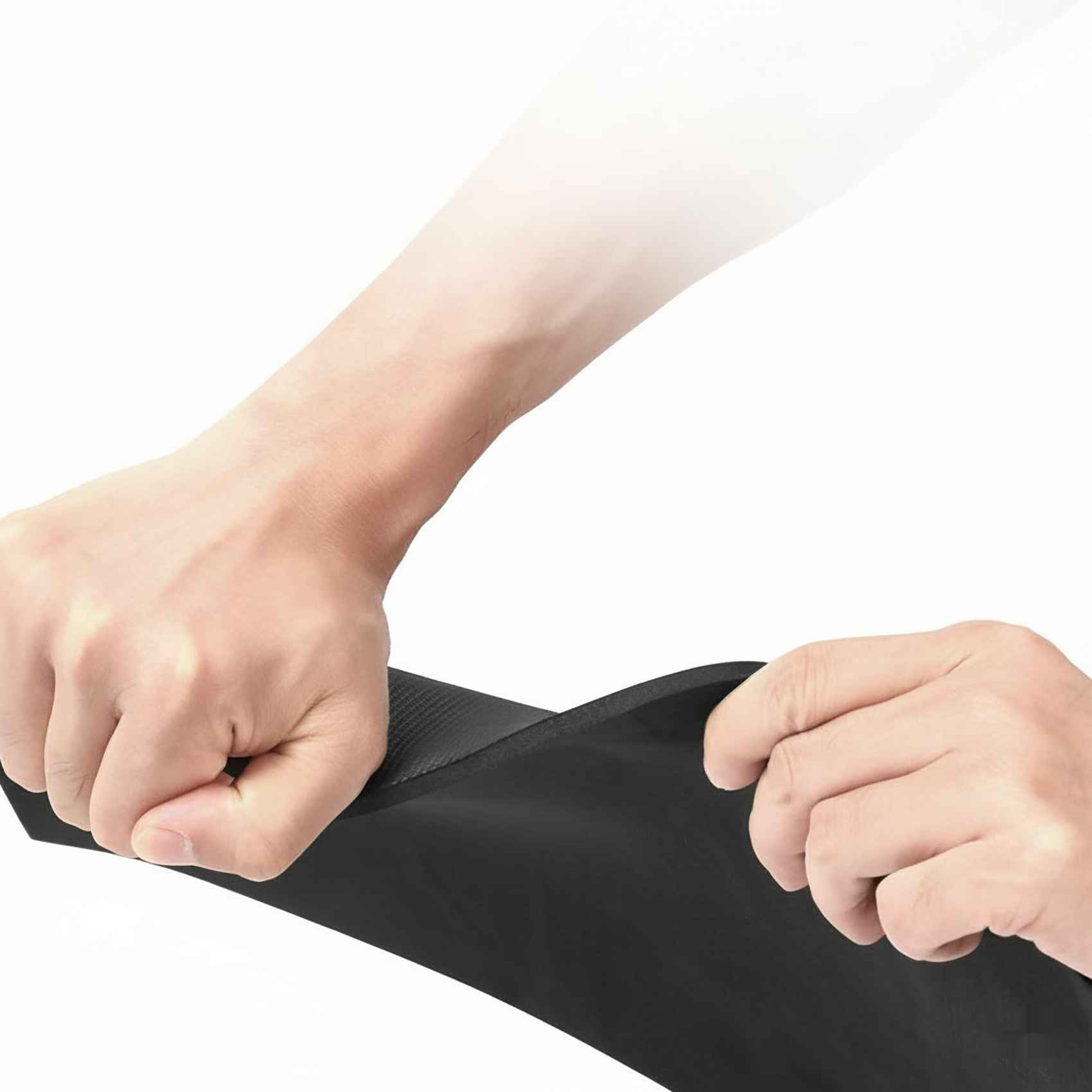 Hände dehnen ein schwarzes, strukturiertes Material vor einem weißen Hintergrund. Das Material ist dick und flexibel.