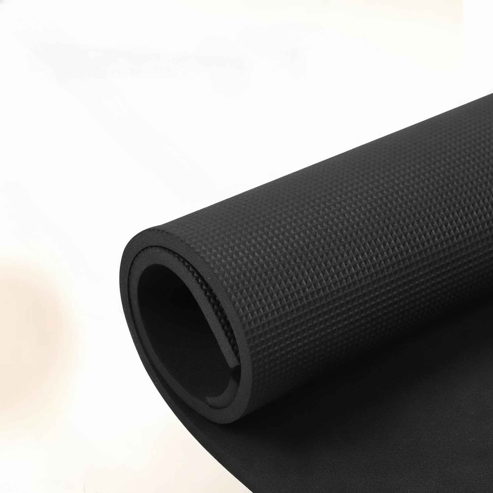 Eine aufgerollte schwarze Yogamatte vor weißem Hintergrund. Die Mattenoberfläche hat ein strukturiertes Muster.