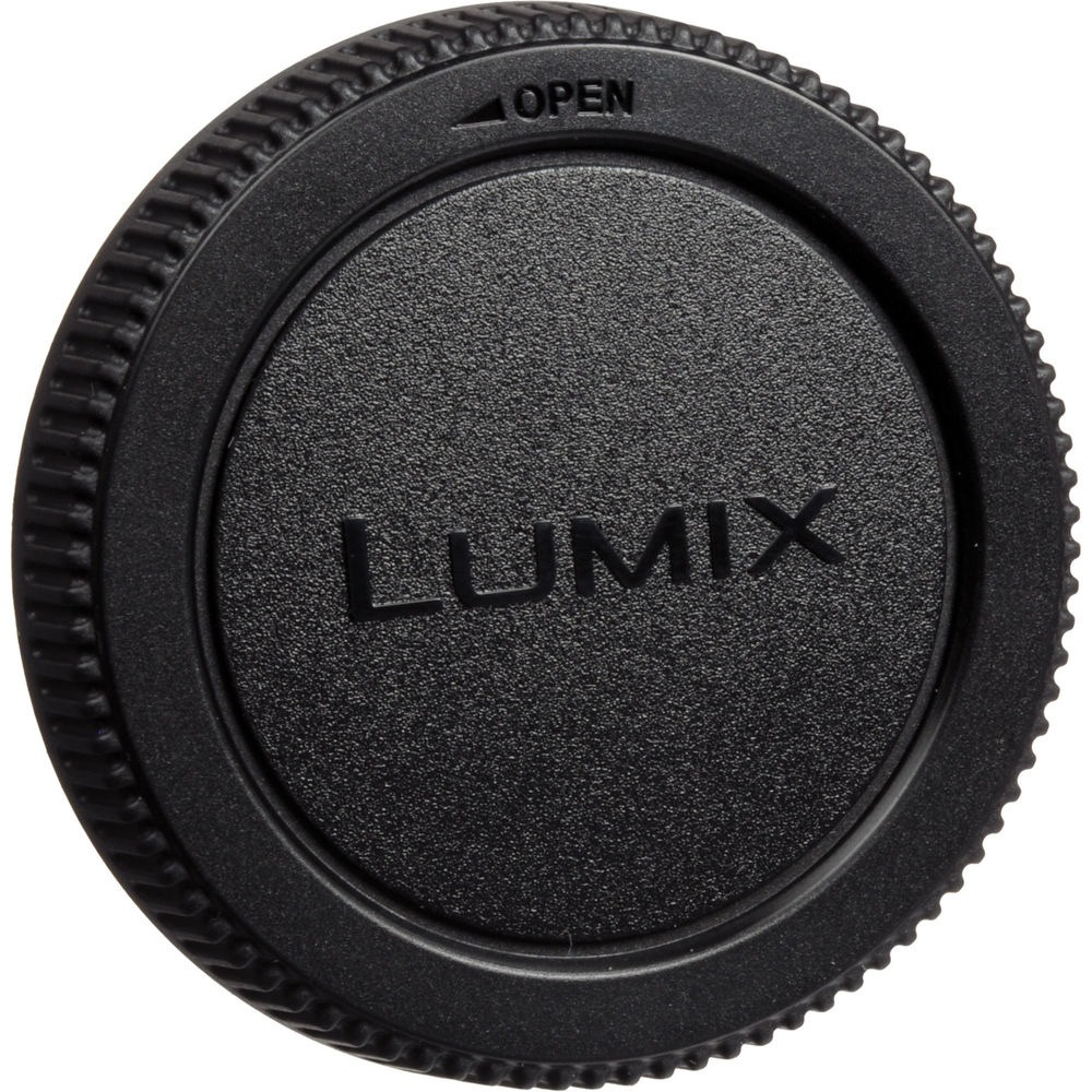 Czarna osłona obiektywu Lumix. Ma wytłoczone słowo 'LUMIX', z napisem 'OPEN' i symbolem strzałki. Osłona ma teksturowaną powierzchnię.