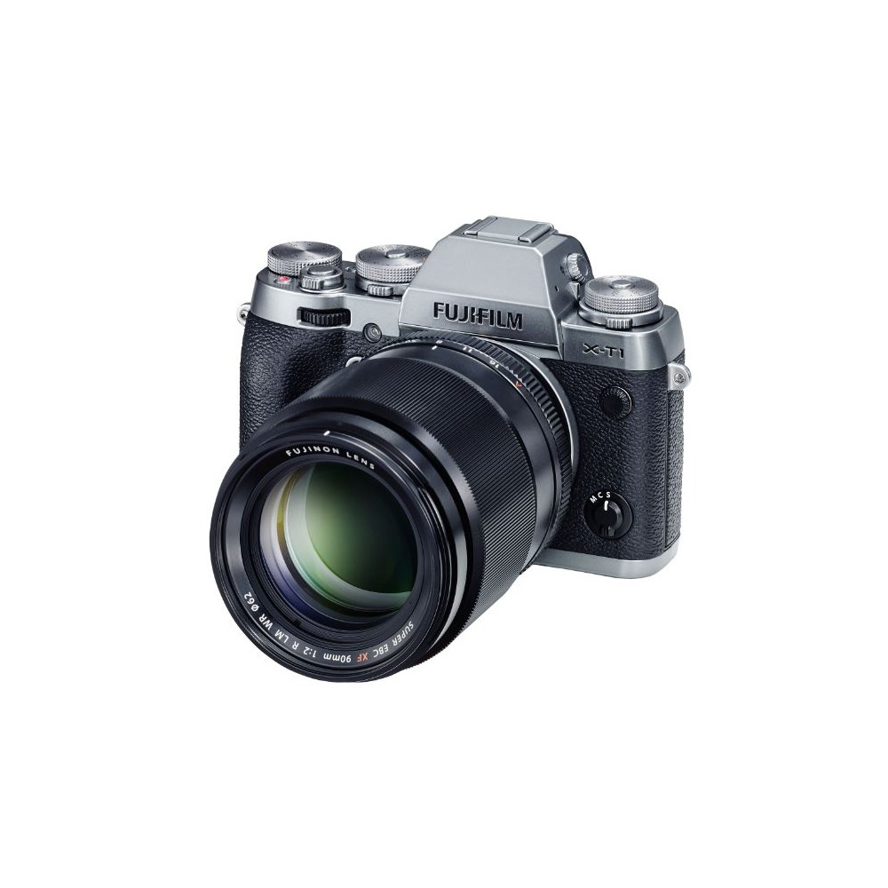 Una cámara Fujifilm X-T1 plateada y negra con una lente. La lente es negra con reflejos verdes. La cámara está sobre un fondo blanco.