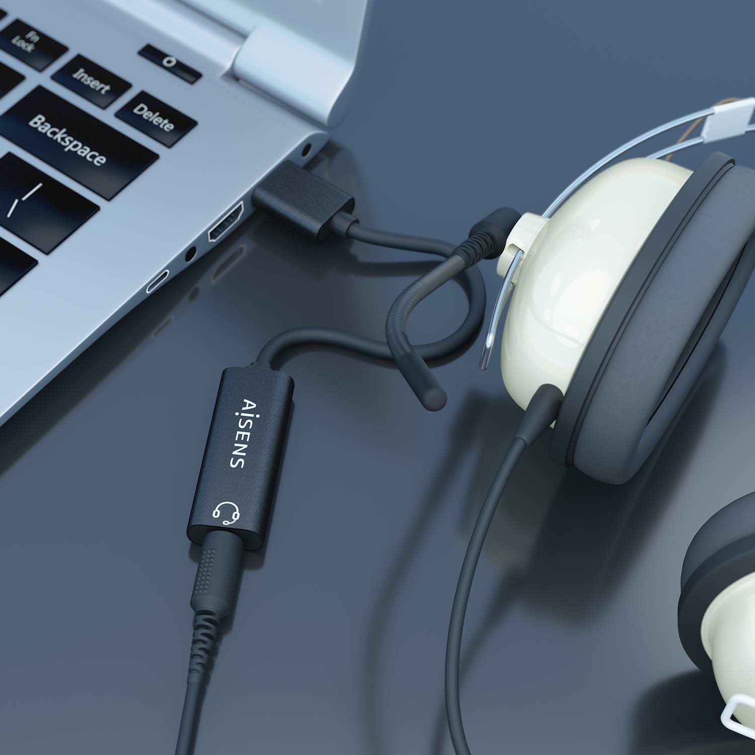 Portátil con auriculares y un adaptador de audio. El adaptador está conectado al portátil y a los auriculares.