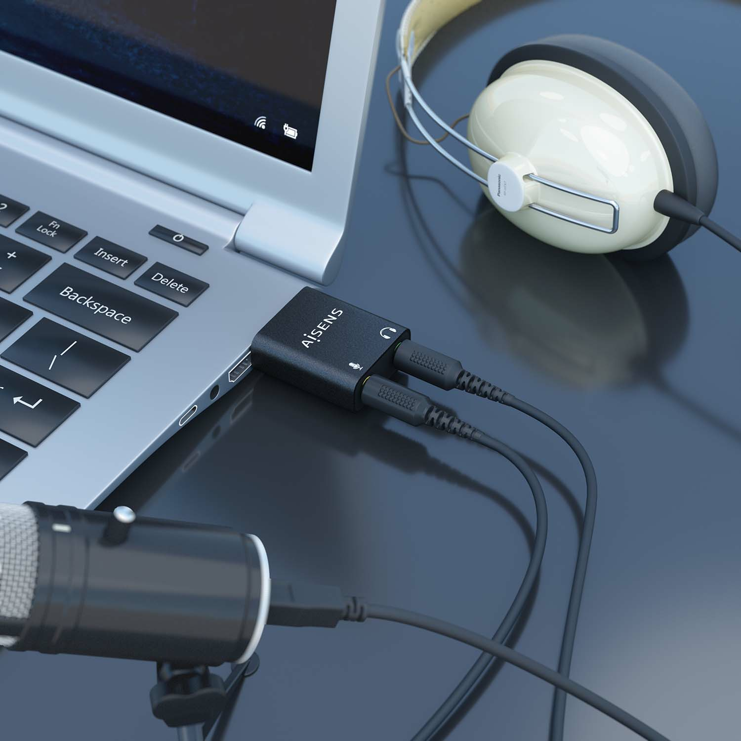Ordenador portátil con un adaptador de audio, micrófono y auriculares. El adaptador se conecta al portátil, con conectores de micrófono y auriculares.