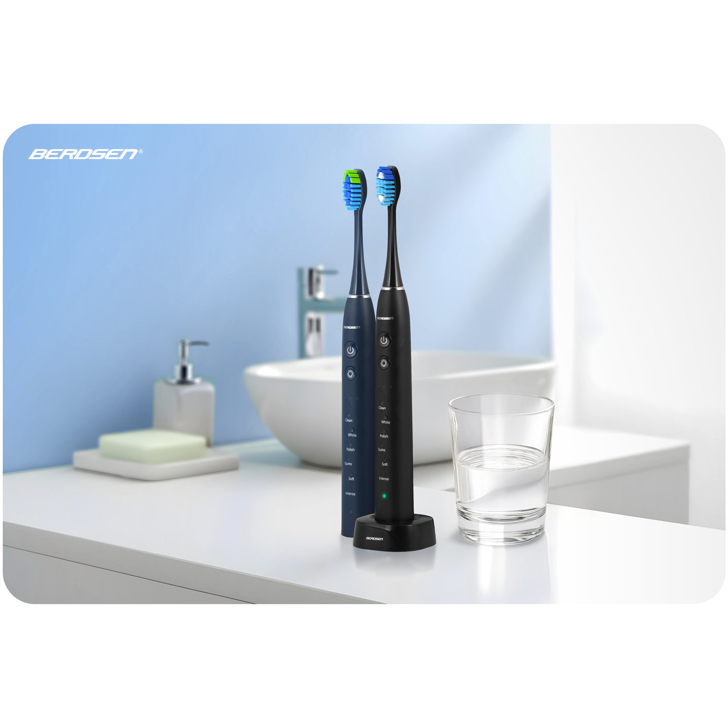 Dwie elektryczne szczoteczki do zębów z niebieskim i zielonym włosiem, umieszczone na białej powierzchni. Szklanka wody, łazienka.