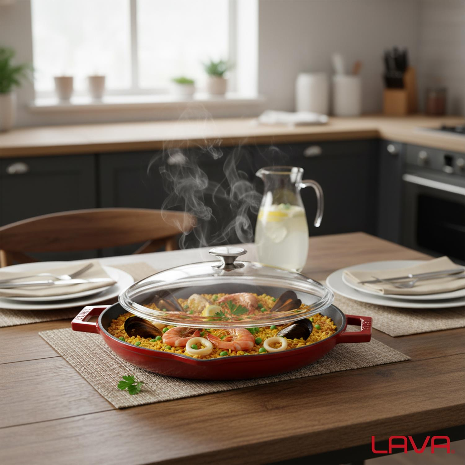 Ahşap bir masa üzerinde deniz ürünleri ile kırmızı bir paella tavası. Üzerinde cam bir kapak var. Arkada pencere ve sürahi ile bir mutfak.