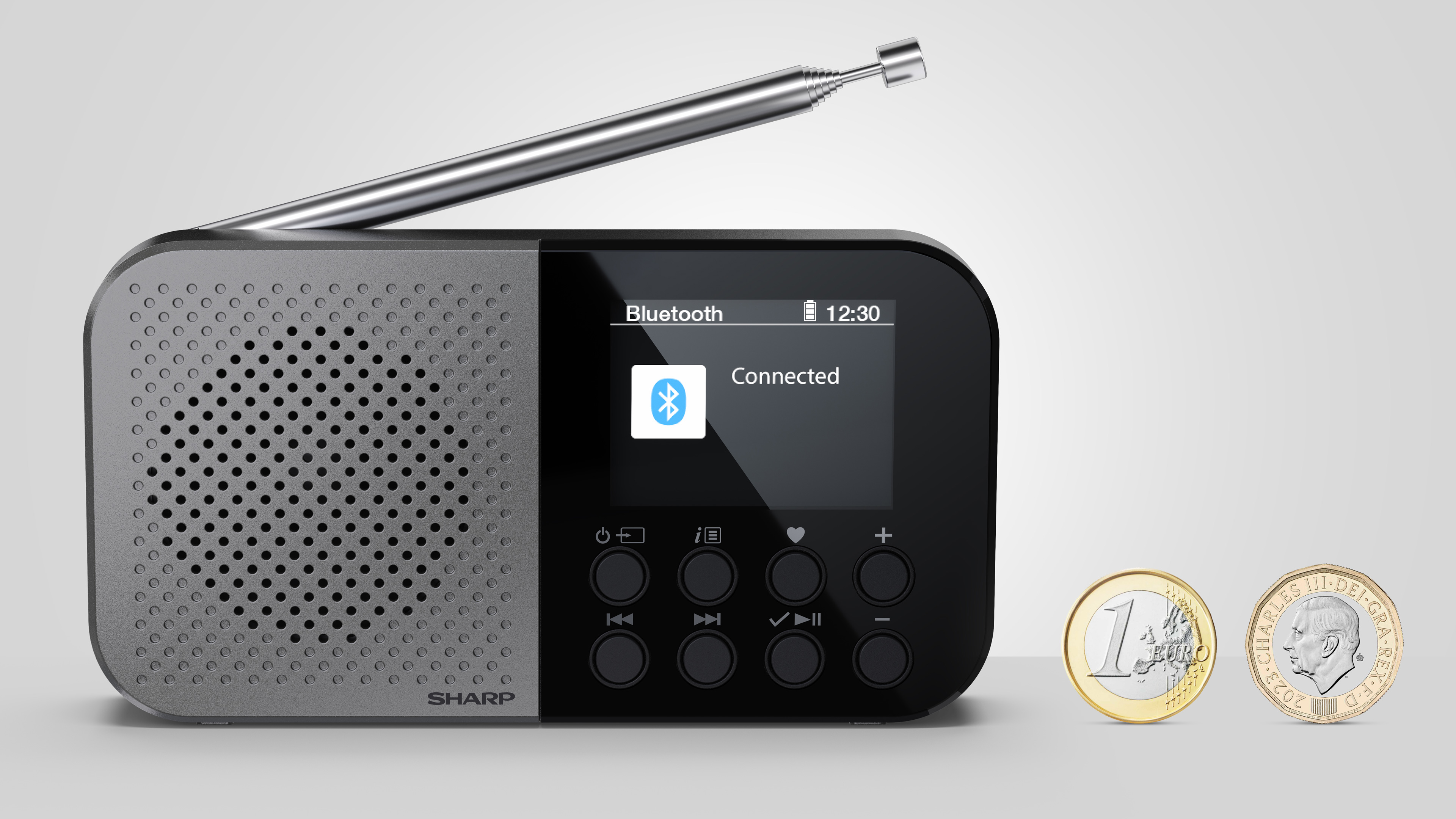 Een grijze en zwarte Sharp-radio met een scherm dat Bluetooth-verbinding toont. Twee munten ernaast.