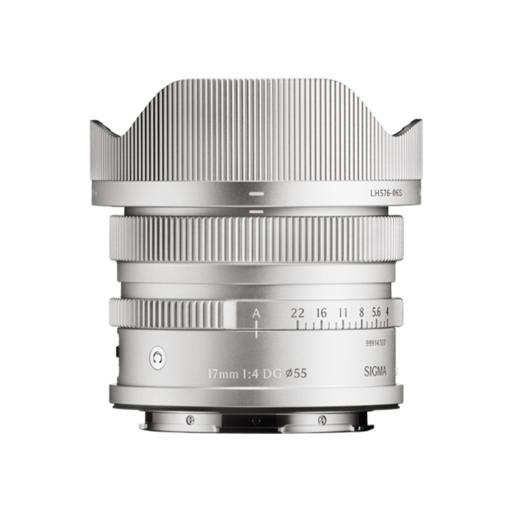 Un obiettivo Sigma 17mm f/4 DC argento. Ha paraluce, ghiere di messa a fuoco e apertura, e marcature. L'obiettivo è isolato su bianco.