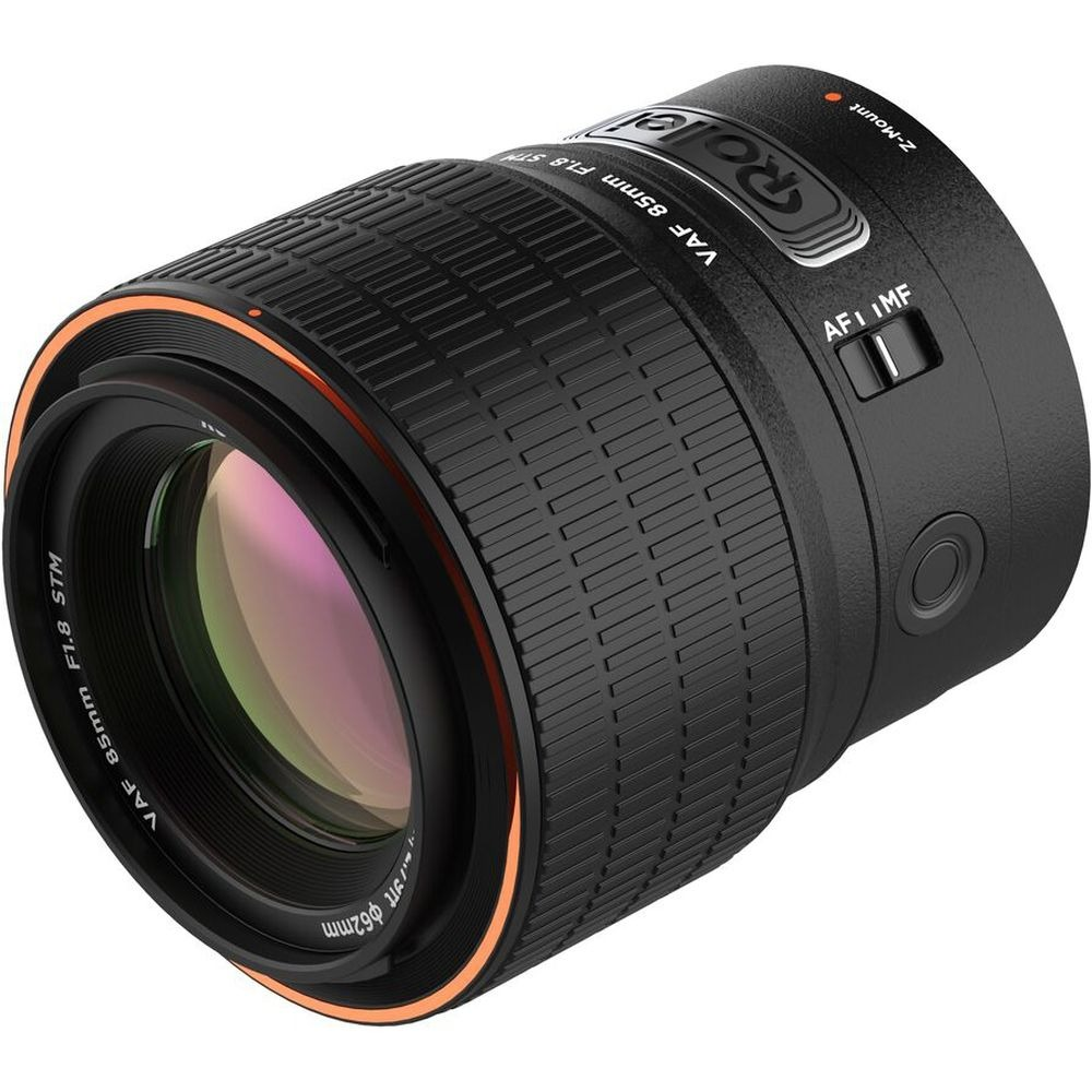Un obiettivo nero per fotocamera con dettagli arancioni. Presenta scritte come 'VAF 85mm F1.8 STM' e 'AFI IMF'.