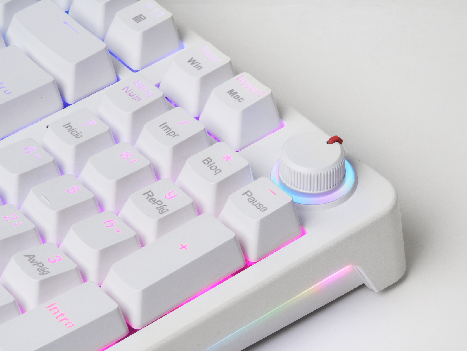 Un teclado blanco con teclas retroiluminadas y una perilla de volumen. Las teclas están etiquetadas con números, símbolos y nombres de funciones.
