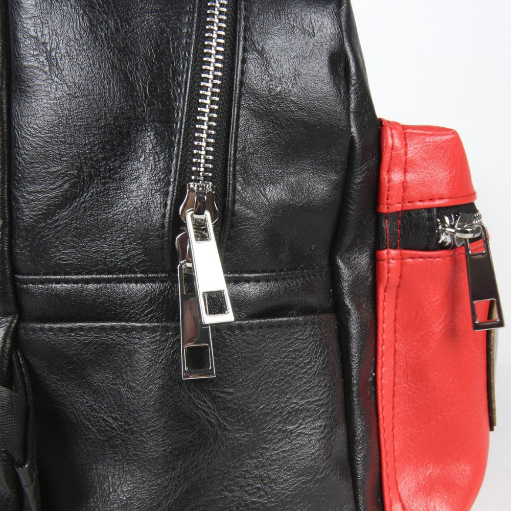 Primer plano de una mochila de cuero negra y roja. Se ven cremalleras plateadas. La bolsa tiene un compartimento principal negro y un bolsillo lateral rojo.