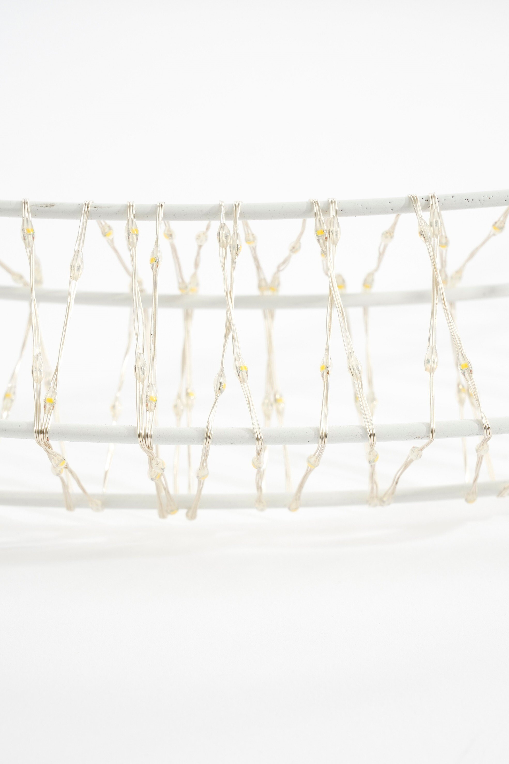 Gros plan d'un objet décoratif blanc avec de petites lumières jaunes, sur fond blanc.