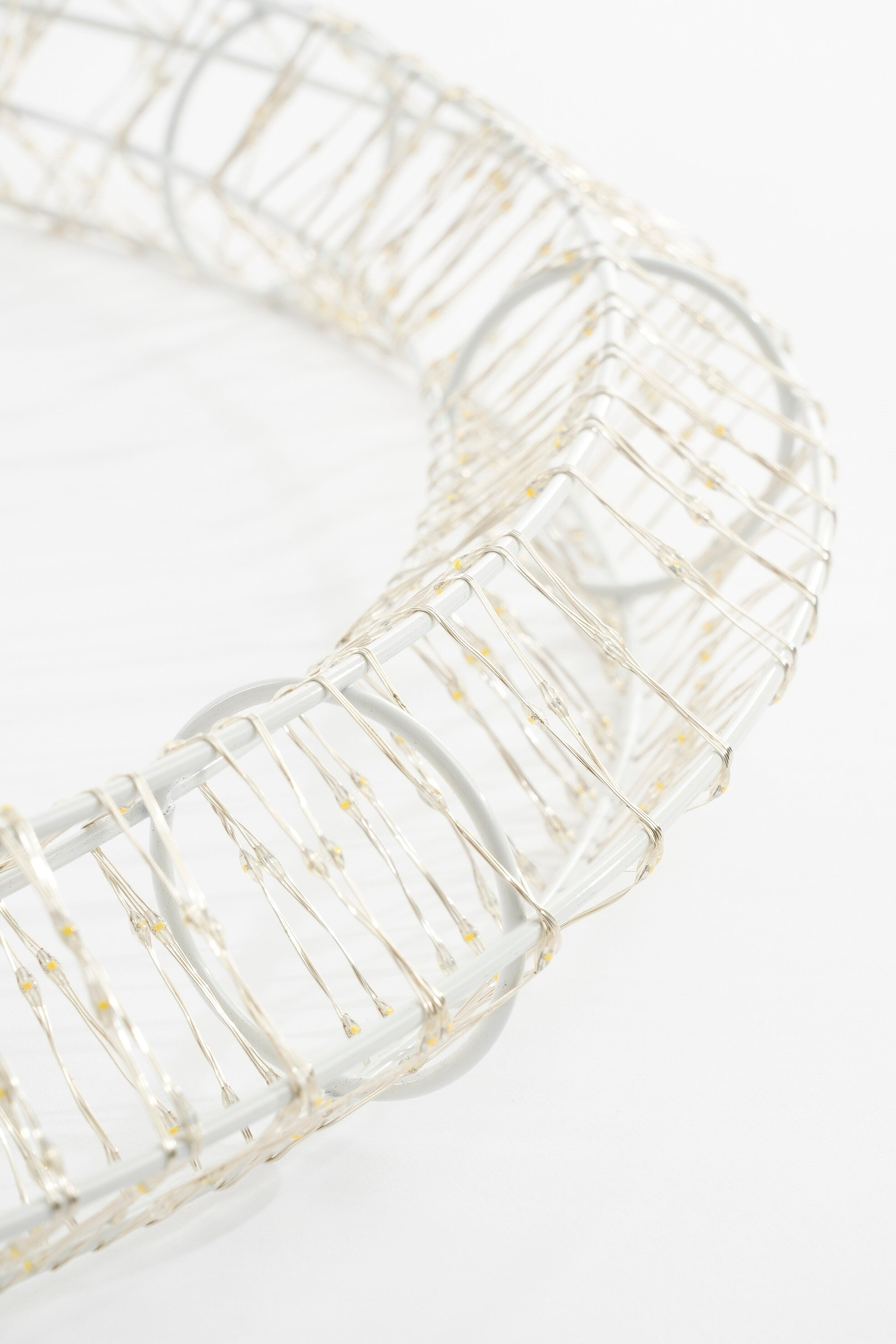 Gros plan d'un luminaire blanc circulaire avec de petites ampoules. Le fond est blanc uni.