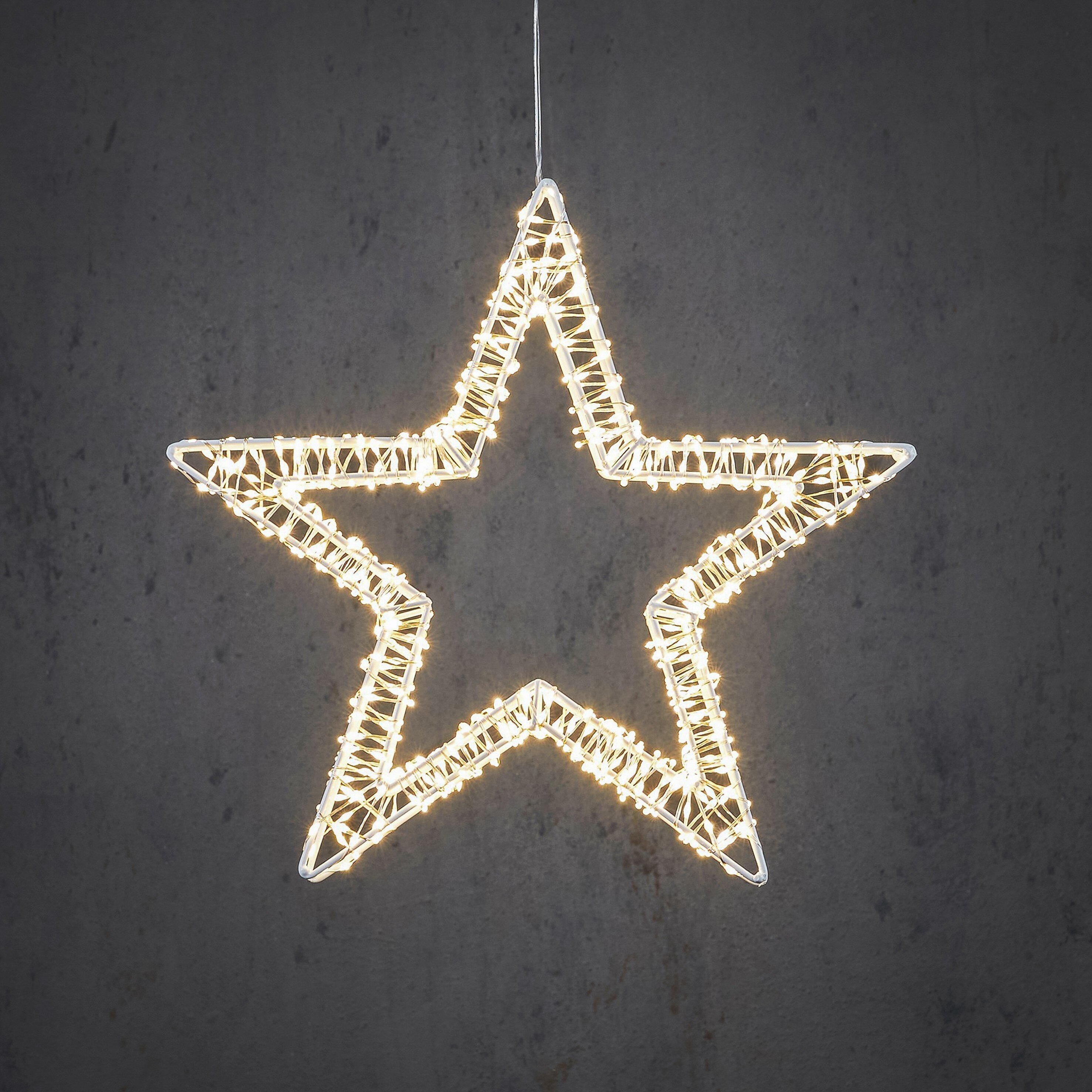 Une décoration en forme d'étoile avec des lumières suspendues sur un fond gris foncé texturé.