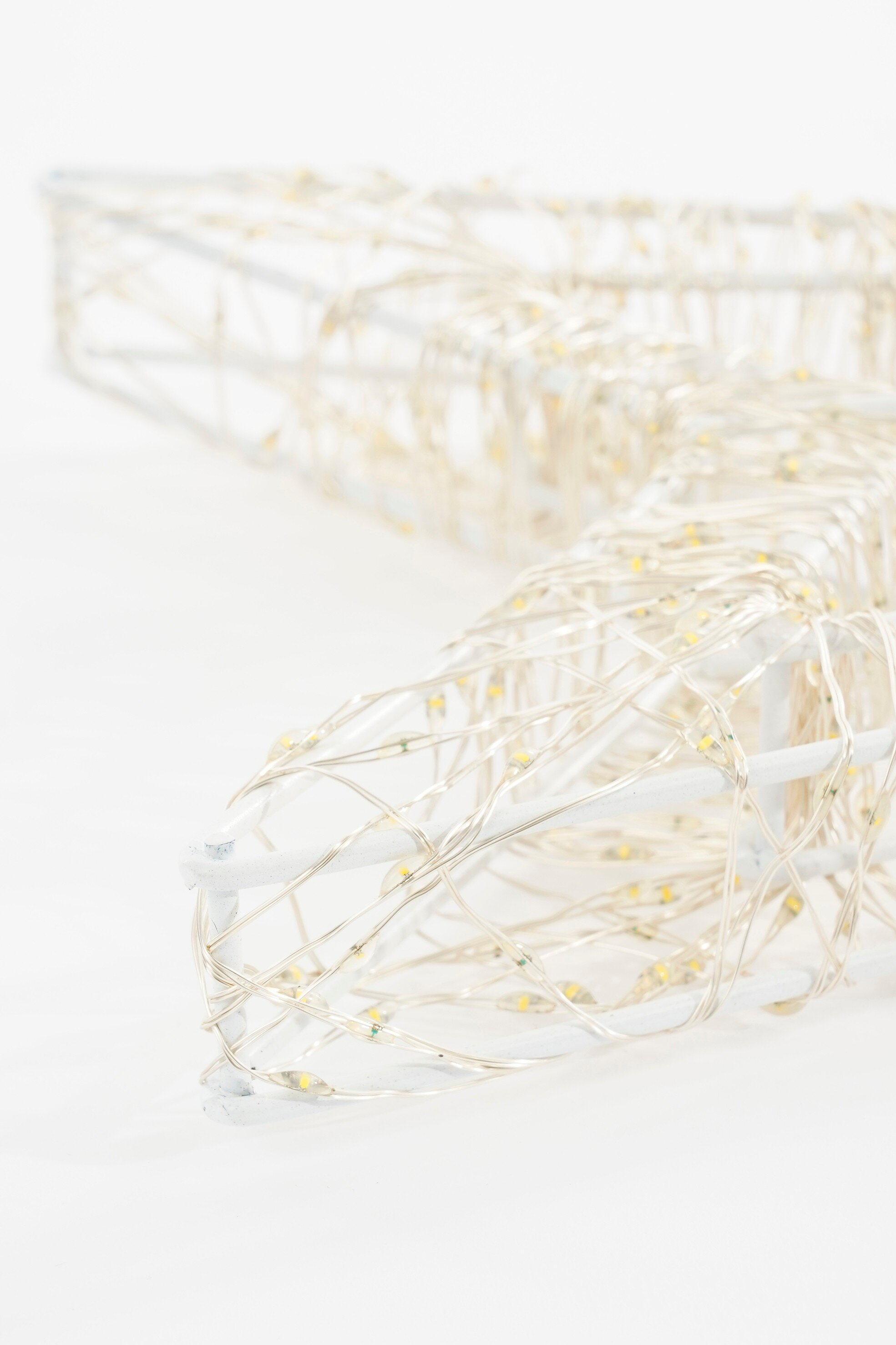 Une décoration blanche en forme d'étoile avec de minuscules lumières. L'étoile est sur fond blanc. Les lumières sont jaunes.