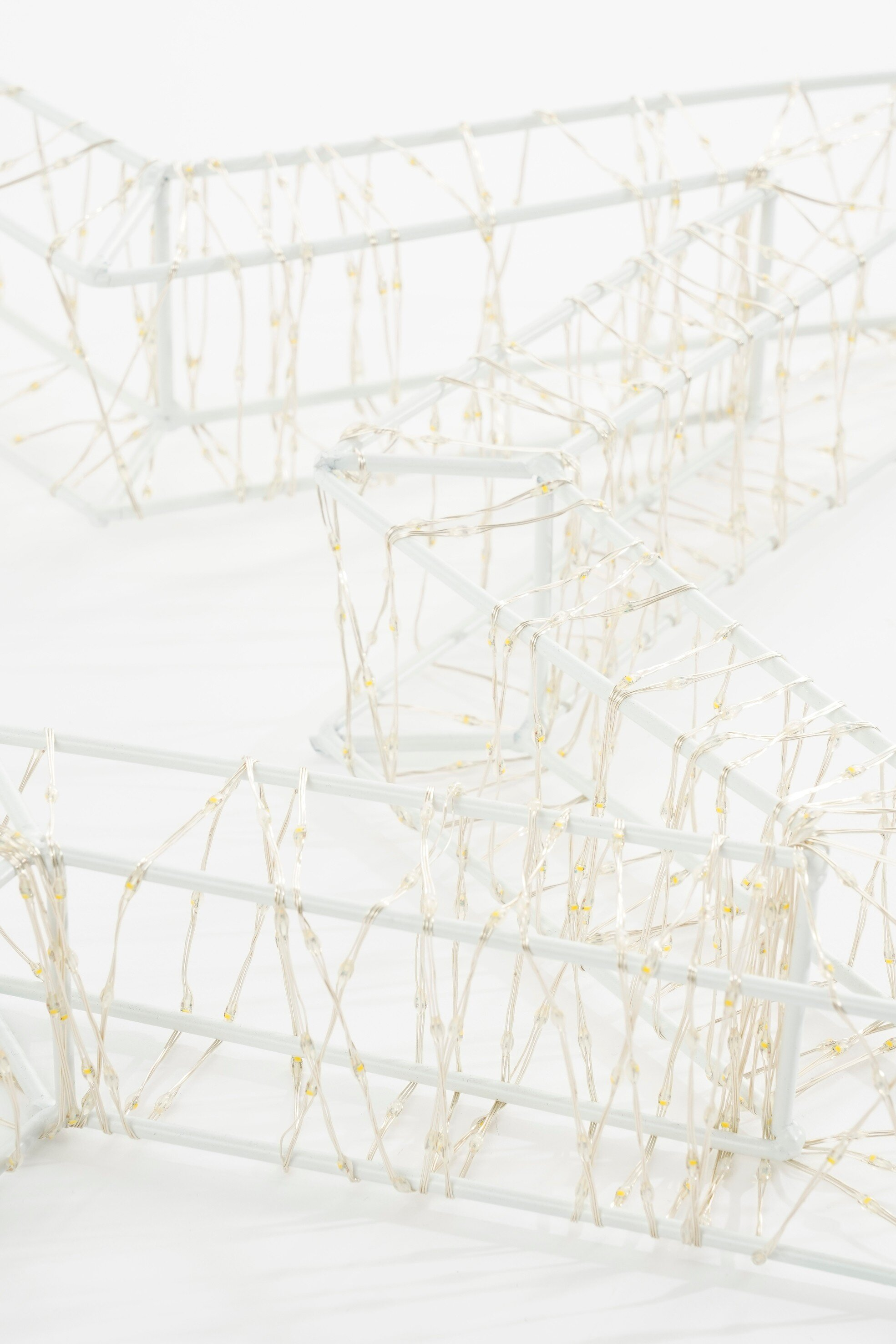 Décoration en métal blanc en forme d'étoile avec guirlande lumineuse sur fond blanc.