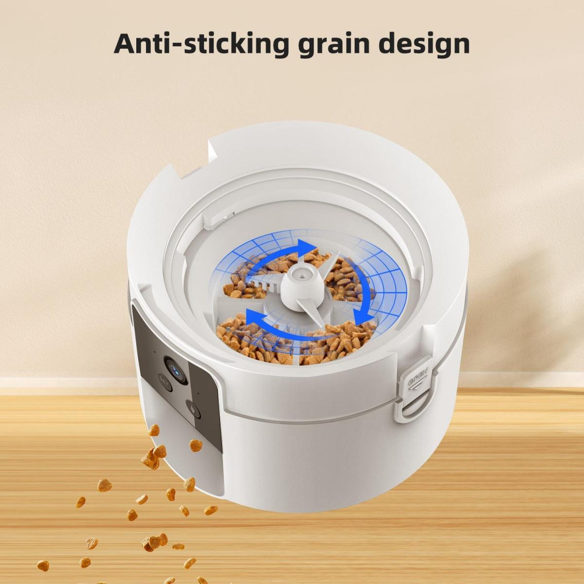 Weißer Tierfutterautomat mit Futter darin. Pfeile zeigen die Ausgabe. Etwas Futter fällt heraus. Text: 'Anti-Haft-Getreide-Design'.
