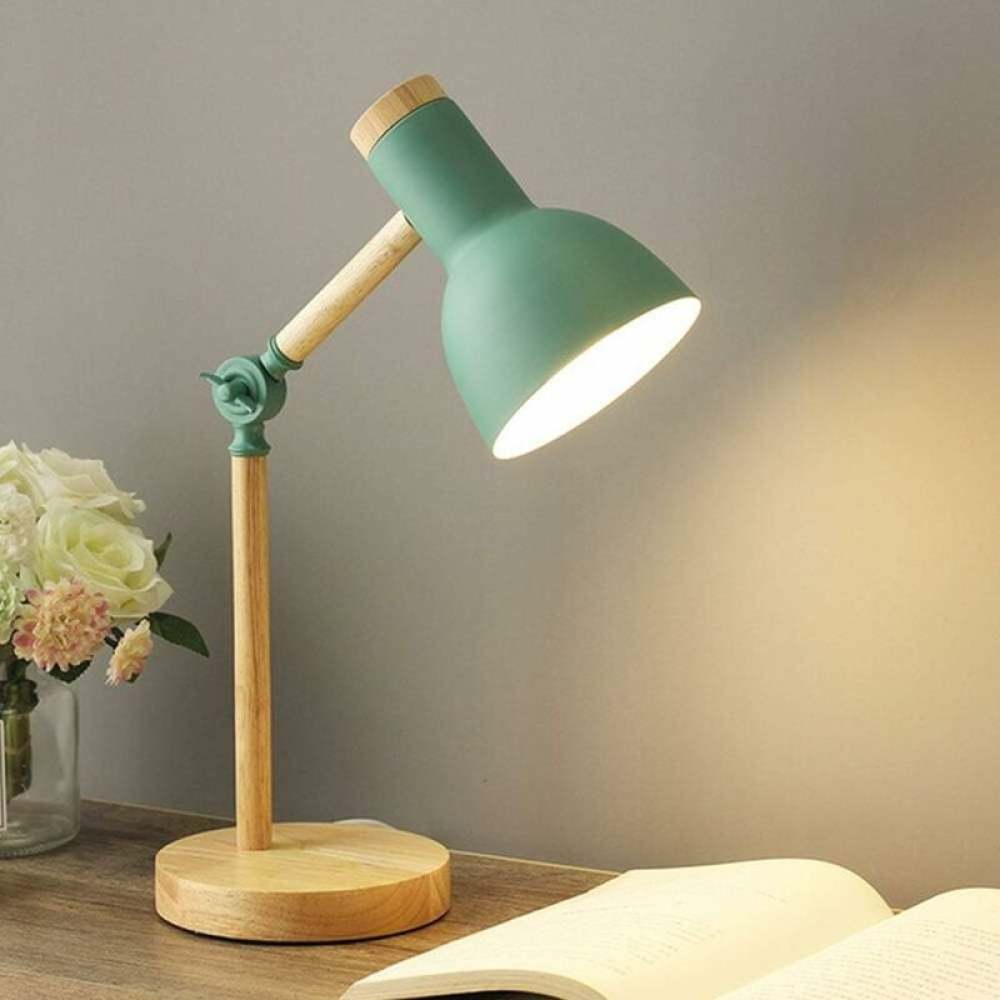 Eine grüne Schreibtischlampe mit Holzakzenten beleuchtet ein offenes Buch. Links steht eine Blumenvase.