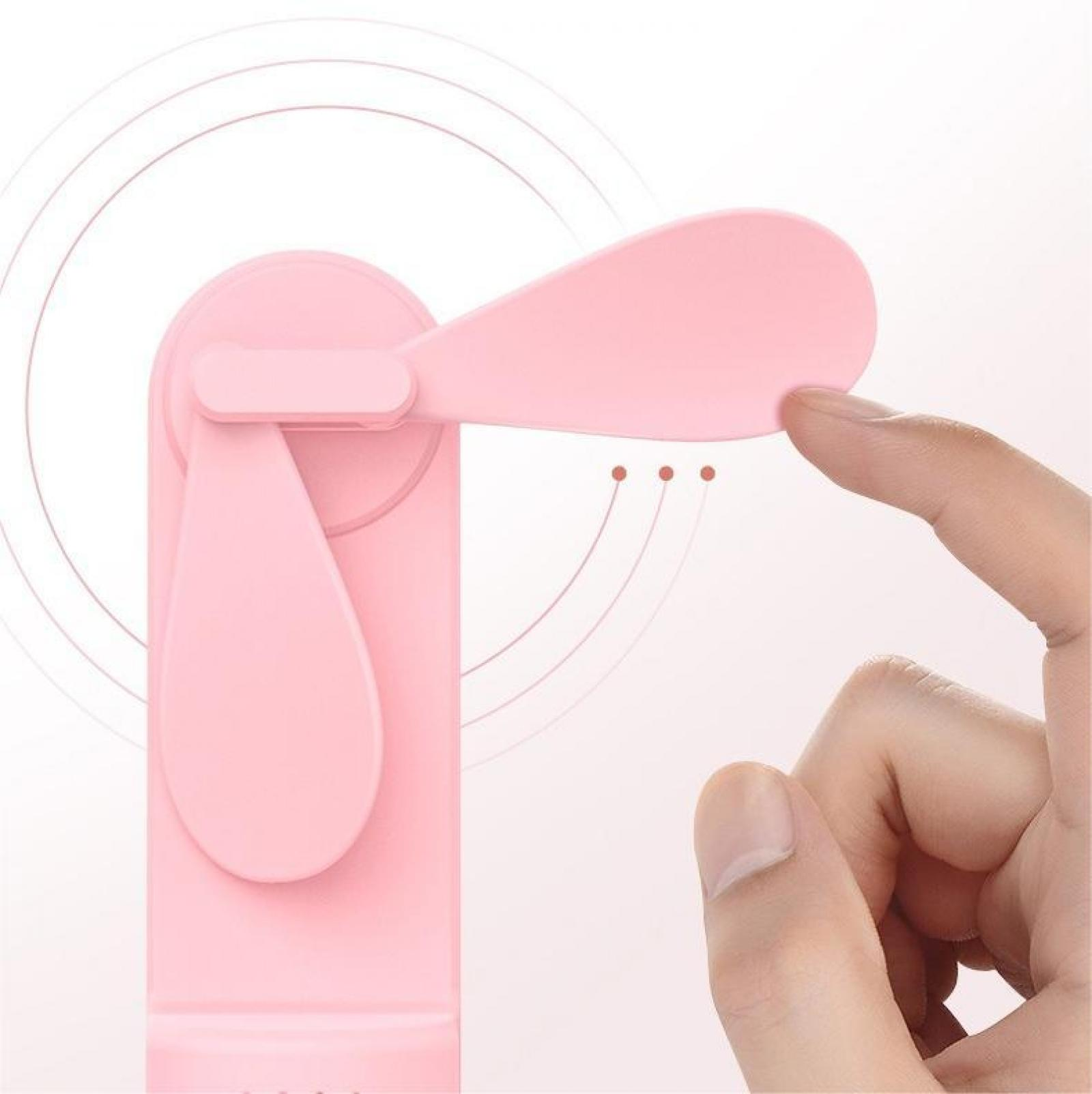 Ein rosa Handventilator wird mit einem Finger berührt. Der Ventilator befindet sich auf weißem Hintergrund, mit drei Punkten und gebogenen Linien.