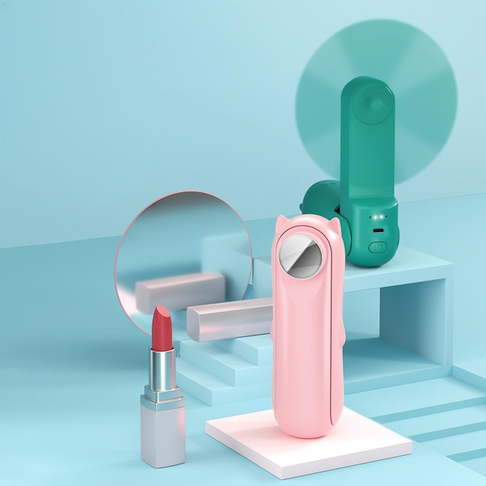 Rosa und grüne Gadgets mit Lippenstift und Spiegel auf blauem Untergrund. Ventilator, Spiegel und Lippenstift sind die Hauptelemente.