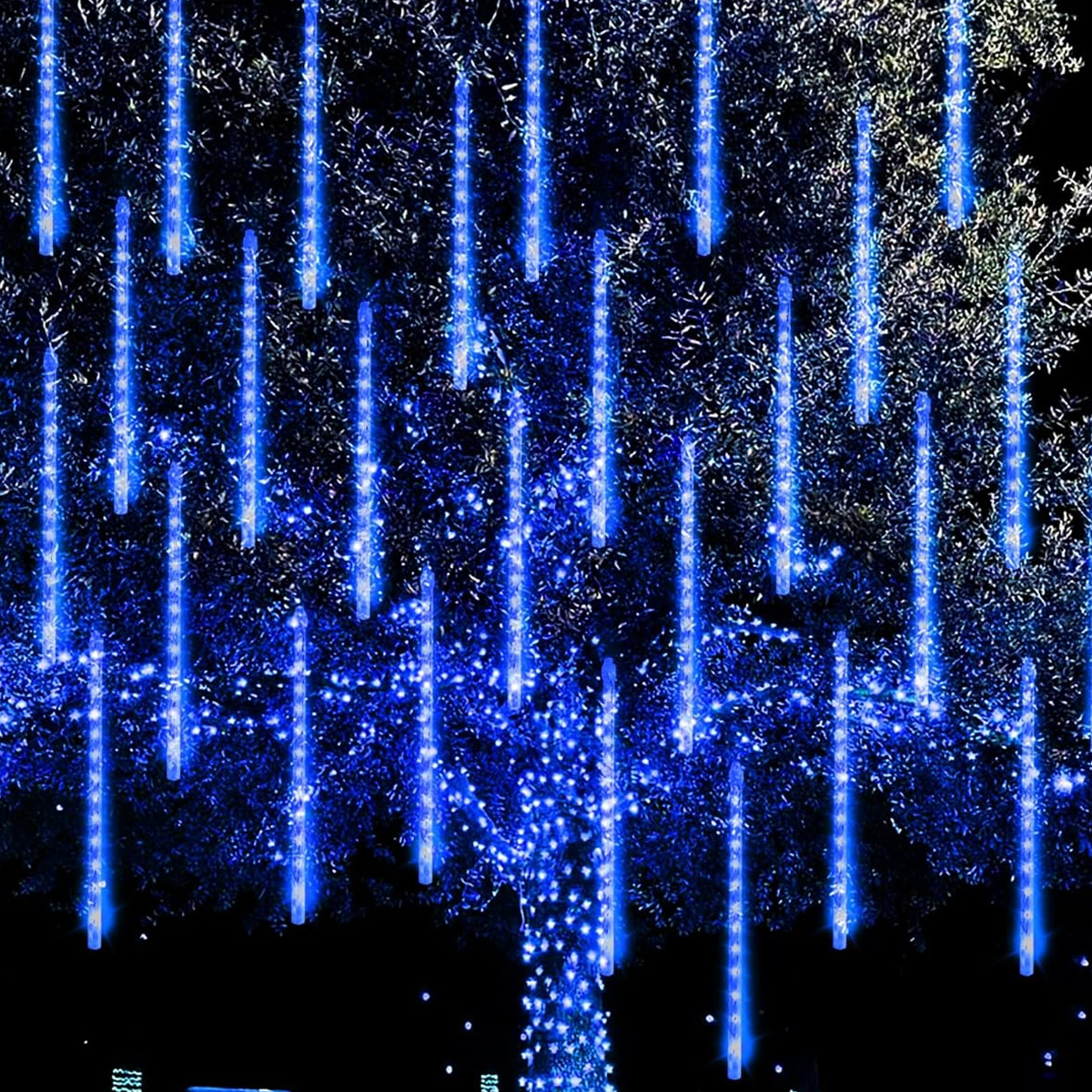 Ein Baum ist mit blauen, vertikalen Lichtern beleuchtet. Die Lichter ähneln fallendem Regen. Der Hintergrund ist dunkel.
