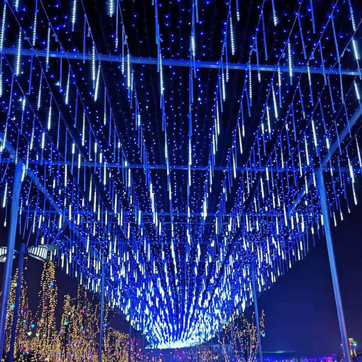 Blaue LED-Lichter hängen von einer Struktur. Lichter ähneln fallenden Sternen. Andere Lichter sind im Hintergrund.