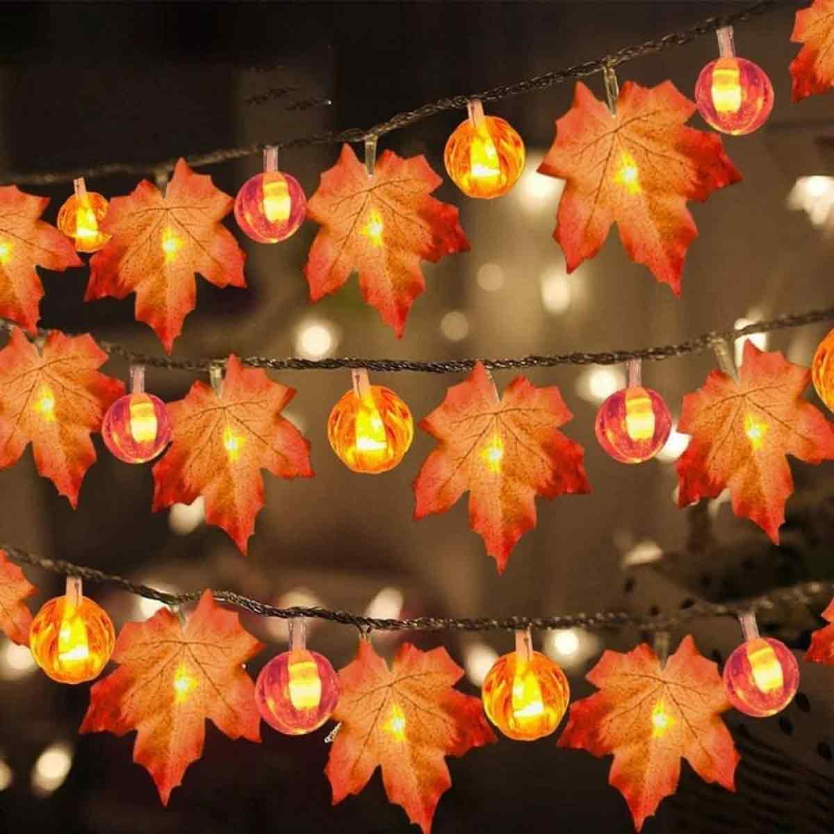 Lichterkette mit Ahornblatt- und runden Glühbirnenformen. Die Blätter sind orange und die Glühbirnen leuchten.