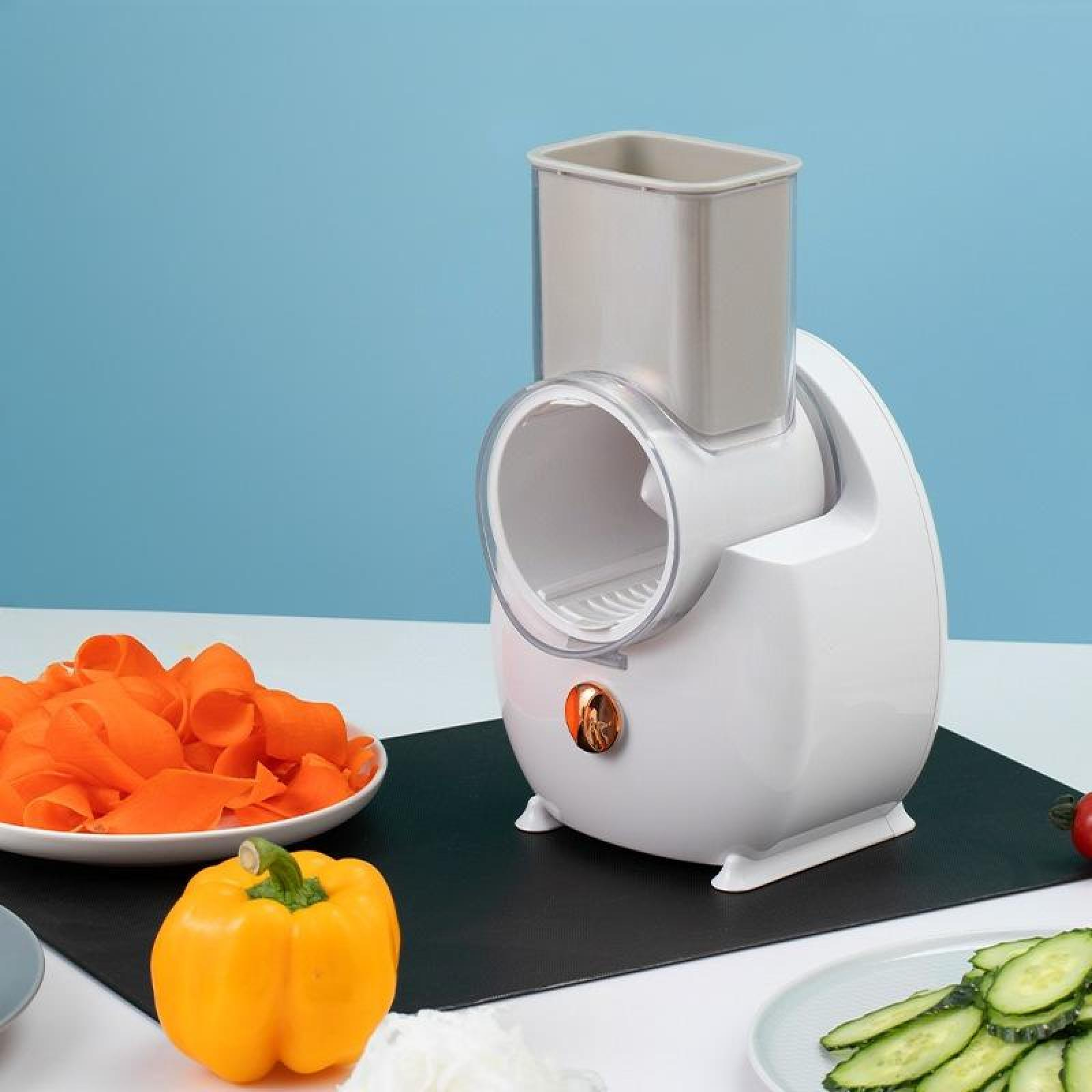 Ein weißer Foodprozessor mit grauem Aufsatz, geschnittene Karotten, gelbe Paprika und geschnittene Gurken auf einem Tisch.