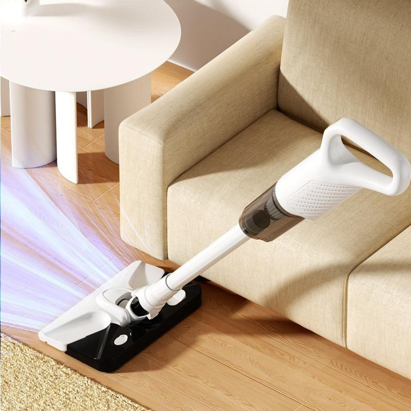 Ein weißer und schwarzer kabelloser Staubsauger auf einem Holzboden neben einem beigen Sofa und einem weißen Tisch.