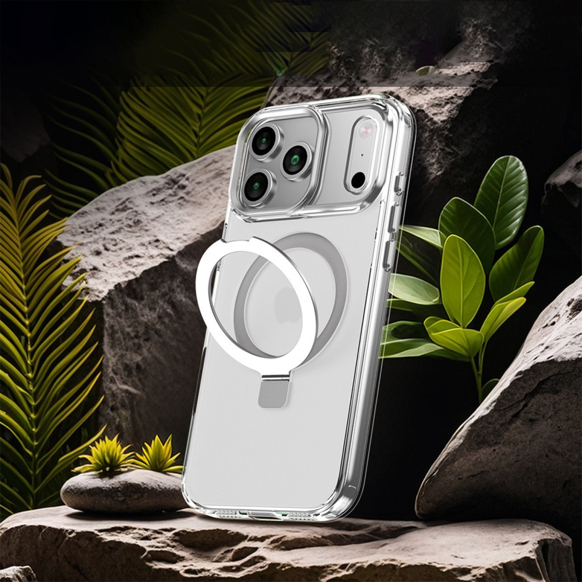 Eine transparente iPhone-Hülle mit weißem Ringständer. Sie liegt auf Felsen, im Hintergrund grüne Pflanzen. Die Hülle hat eine Kamera.