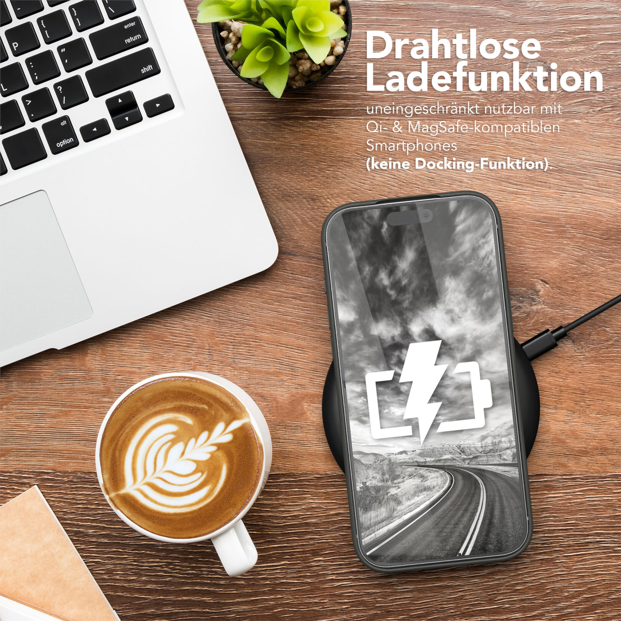 Telefon lädt auf einem Pad, Kaffee, Laptop und Pflanze auf einem Holztisch.