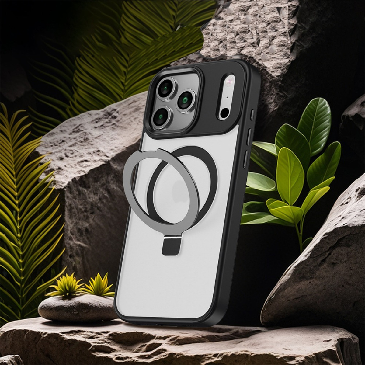 Ein iPhone mit einer schwarzen und transparenten Hülle mit einem Ringhalter auf einem Felsen, umgeben von grünen Blättern und Pflanzen.