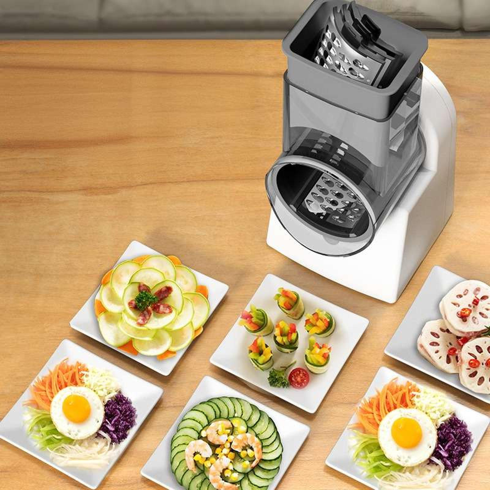 Ein Lebensmittelreibe steht neben Tellern mit angerichteten Speisen, darunter Salate, Brötchen und geschnittenes Gemüse, alles auf einer Holzoberfläche.