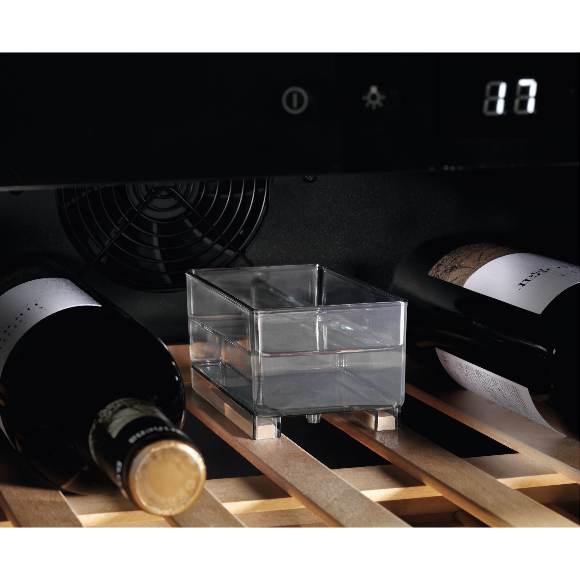 Dentro de una nevera para vinos, se ven botellas, una caja transparente y una pantalla digital que muestra '87'.