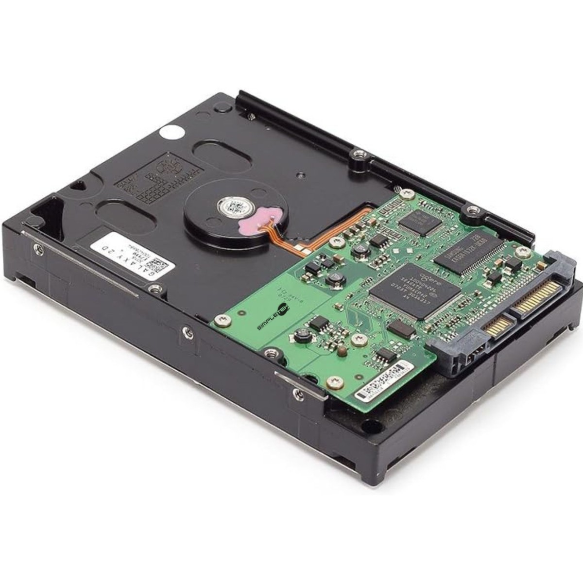 Un disco rigido su una superficie bianca. Ha un involucro in metallo nero e una scheda a circuito stampato verde con chip e connettori.