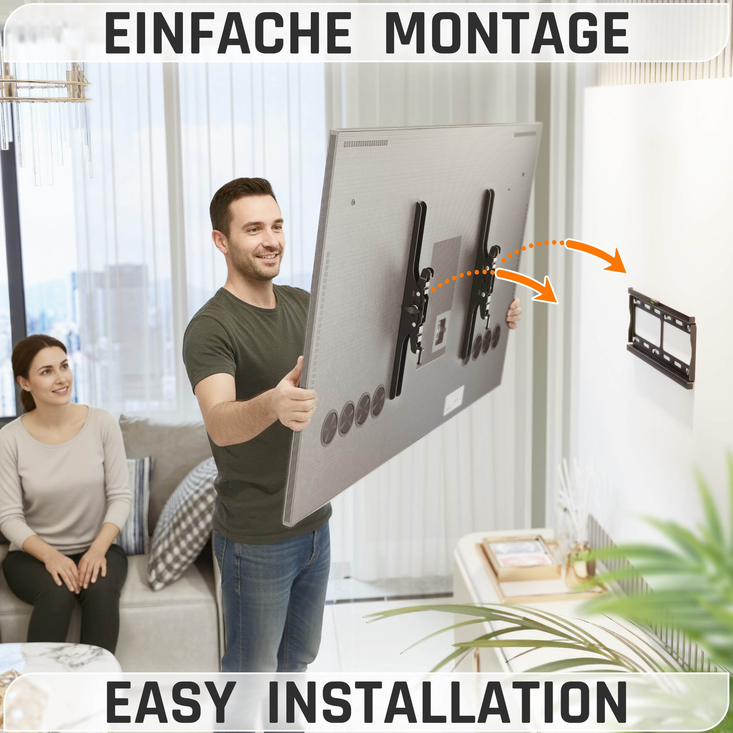 Ein Mann hält einen Fernseher und zeigt die einfache Installation. Eine Frau sitzt auf einem Sofa. Der Fernseher ist an der Wand montiert.